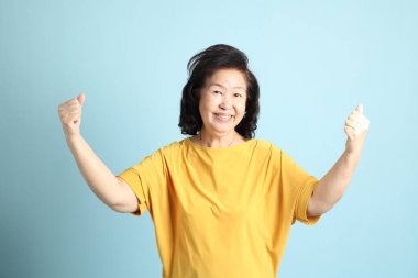 Mavi arka plandaki kıdemli Asyalı kadın..