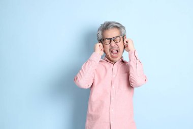 The senior Asian man standing on the blue background with pink shirt.