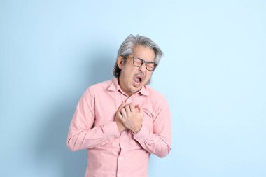 The senior Asian man standing on the blue background with pink shirt.