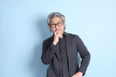 The senior Asian businessman standing on the blue background.