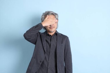 The senior Asian businessman standing on the blue background.