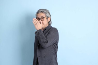 The senior Asian businessman standing on the blue background.