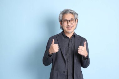 The senior Asian businessman standing on the blue background.