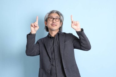 The senior Asian businessman standing on the blue background.
