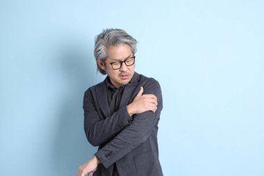 The senior Asian businessman standing on the blue background.