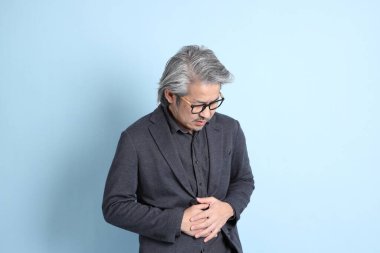 The senior Asian businessman standing on the blue background.