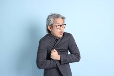 The senior Asian businessman standing on the blue background.