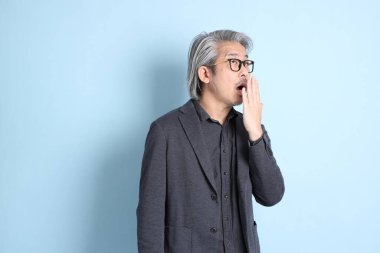 The senior Asian businessman standing on the blue background.