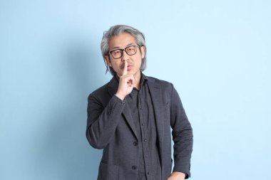 The senior Asian businessman standing on the blue background.