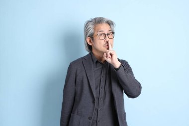 The senior Asian businessman standing on the blue background.