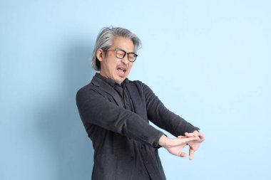 The senior Asian businessman standing on the blue background.