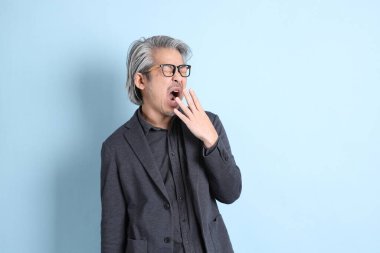 The senior Asian businessman standing on the blue background.