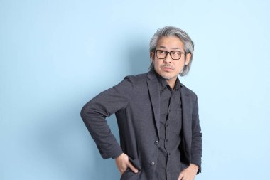The senior Asian businessman standing on the blue background.
