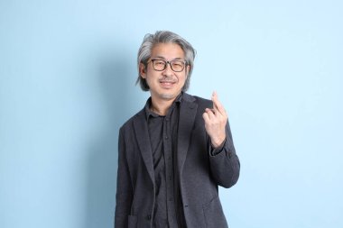 The senior Asian businessman standing on the blue background.