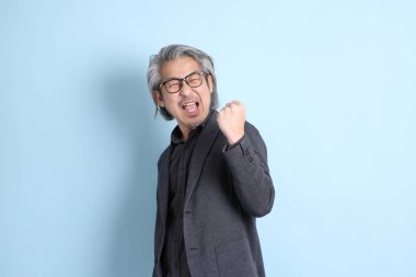 The senior Asian businessman standing on the blue background.