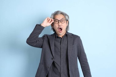 The senior Asian businessman standing on the blue background.