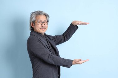 The senior Asian businessman standing on the blue background.