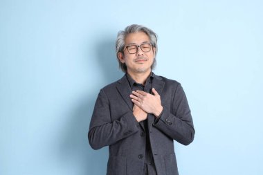 The senior Asian businessman standing on the blue background.