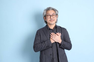 The senior Asian businessman standing on the blue background.