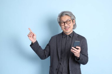 The senior Asian businessman standing on the blue background.