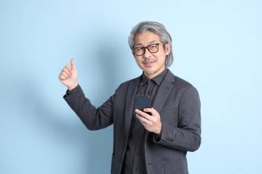 The senior Asian businessman standing on the blue background.