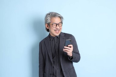 The senior Asian businessman standing on the blue background.