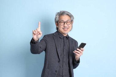 The senior Asian businessman standing on the blue background.