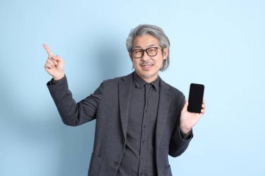 The senior Asian businessman standing on the blue background.