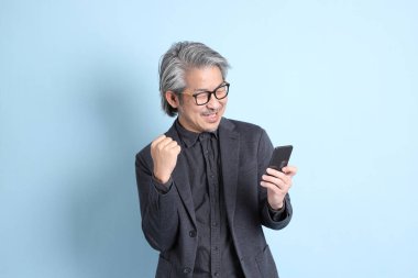 The senior Asian businessman standing on the blue background.