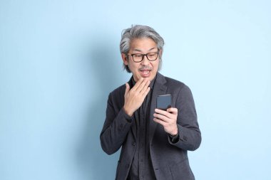 The senior Asian businessman standing on the blue background.