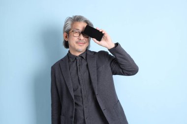 The senior Asian businessman standing on the blue background.