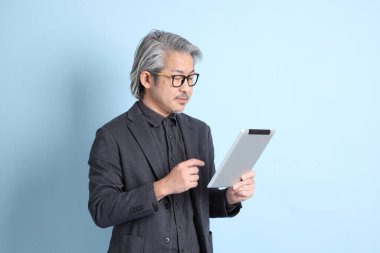 The senior Asian businessman standing on the blue background.