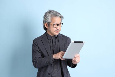 The senior Asian businessman standing on the blue background.