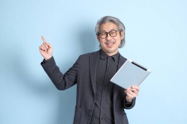 The senior Asian businessman standing on the blue background.