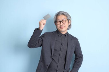 The senior Asian businessman standing on the blue background.