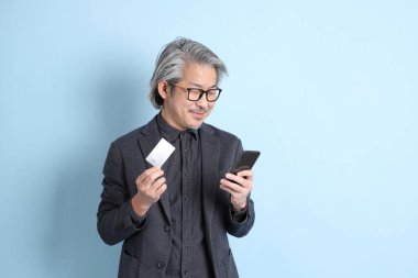 The senior Asian businessman standing on the blue background.
