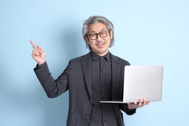 The senior Asian businessman standing on the blue background.