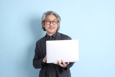 The senior Asian businessman standing on the blue background.