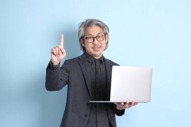 The senior Asian businessman standing on the blue background.