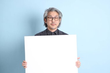 The senior Asian businessman standing on the blue background.