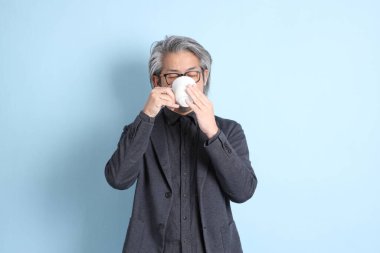 The senior Asian businessman standing on the blue background.