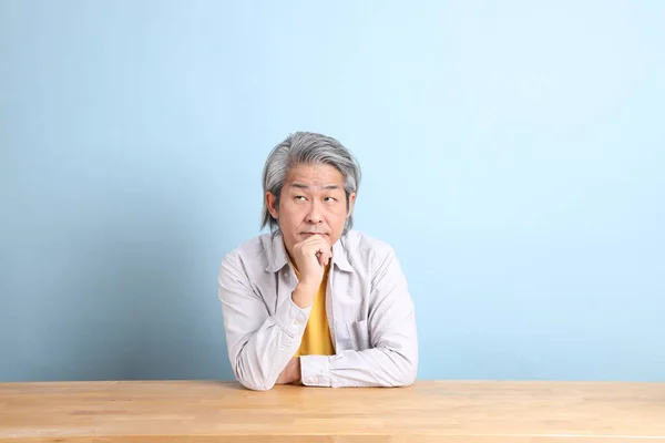 Senior Asian Man Grey Shirt Sitting Working Desk Blue Background — Stockfoto