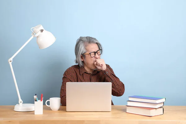 Старший Азіат Працює Ноутбуці Столом Синім Фоном — стокове фото