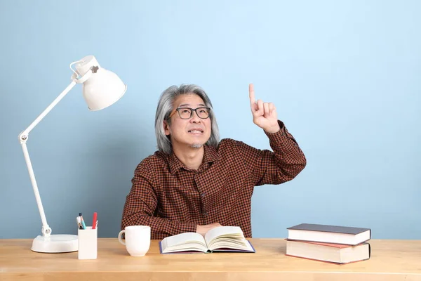 Senior Asian Man Reading Books Desk Blue Background — Stockfoto