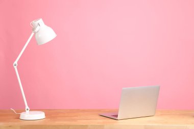 The working desk without people on the pink wall.