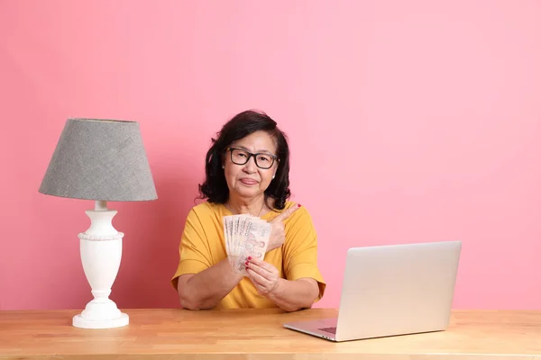 Starsza Azjatka Pracująca Laptopem Siedzącym Przy Biurku Różowym Tłem — Zdjęcie stockowe