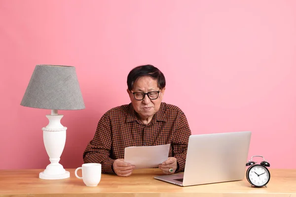 Starszy Azjata Siedzi Przy Biurku Laptopem Różowym Tle — Zdjęcie stockowe