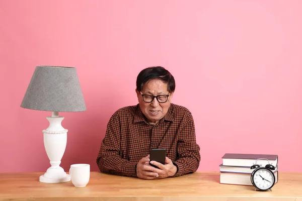 Senior Asian Man Sitting Working Desk Using Smart Phone Pink — Stockfoto