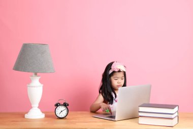 The cute Asian girl learning from internet by laptop with the pink background.