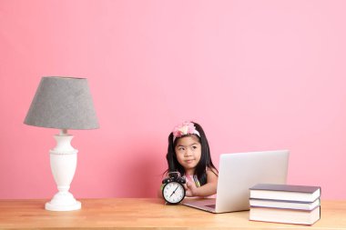 The cute Asian girl learning from internet by laptop with the pink background.